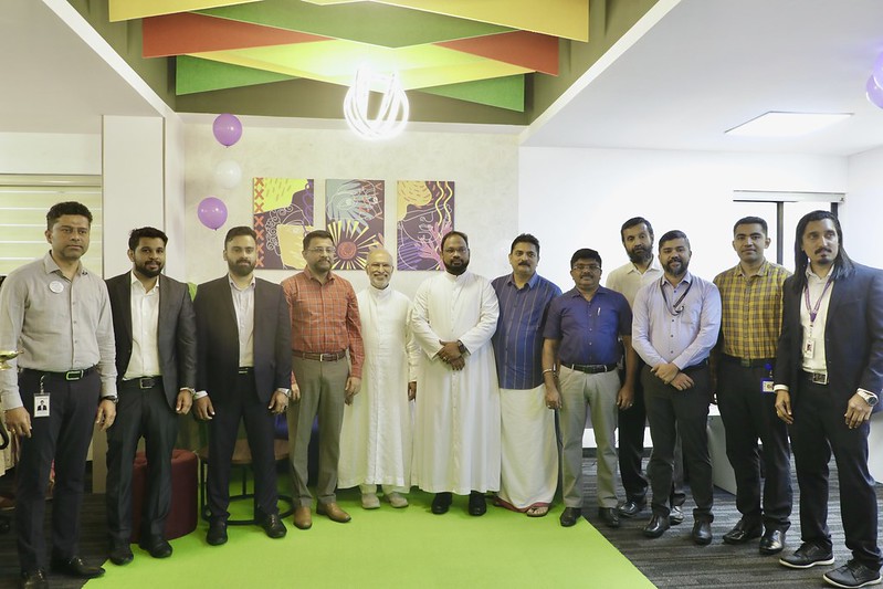 Col Sanjeev Nair (Retd), Dr. Abraham Mulamoottil, Father Febin, Mr. Abhinand V Nair, Mr. Vasanth Varada, and other guests and employees at the launch.